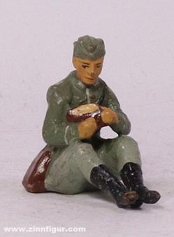 Soldat assis coupant du pain 
